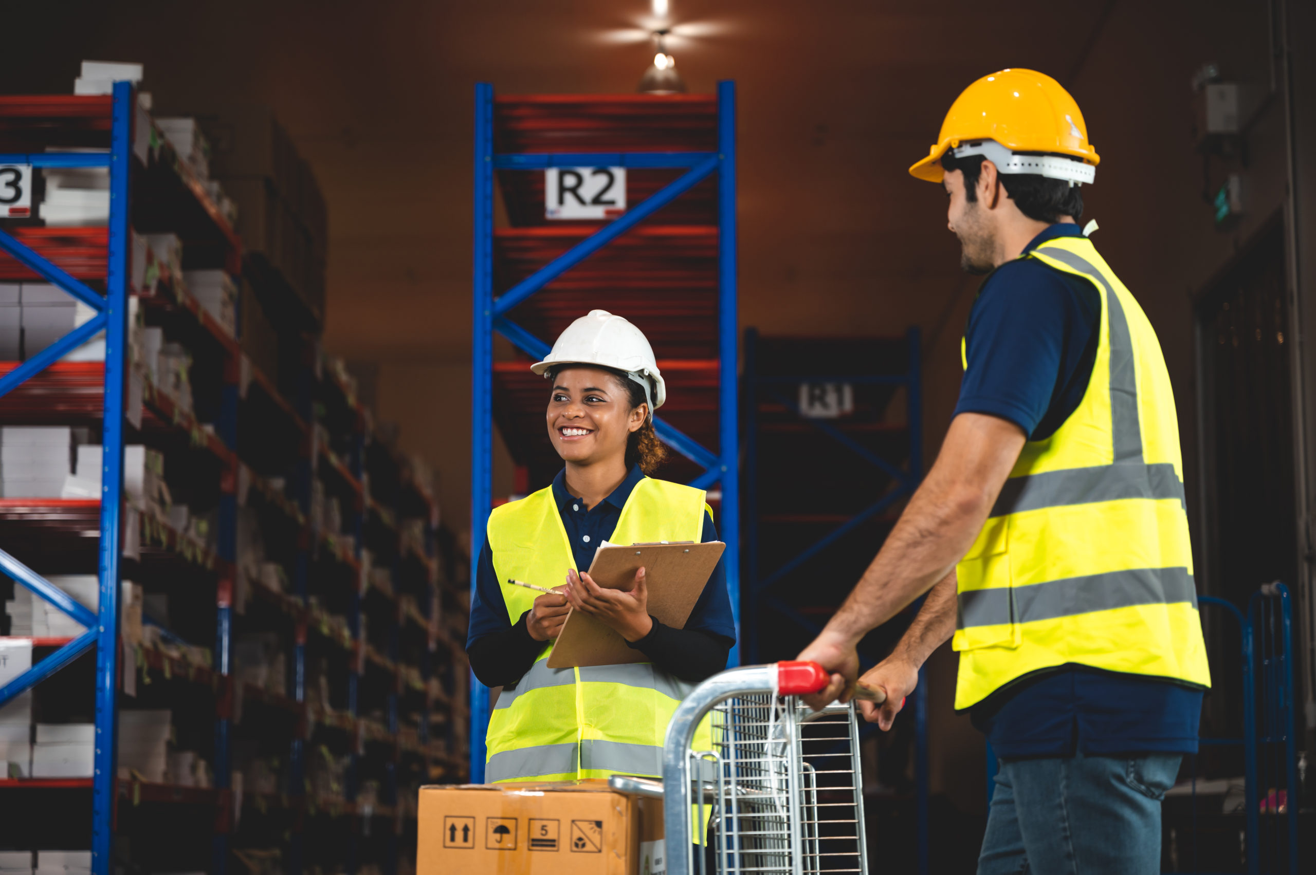 Employee Engagement: Two warehouse workers are speaking, wearing proper PPE for safety