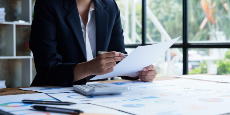 ESG Audit: A business woman is reviewing several reports laid out across her desk.