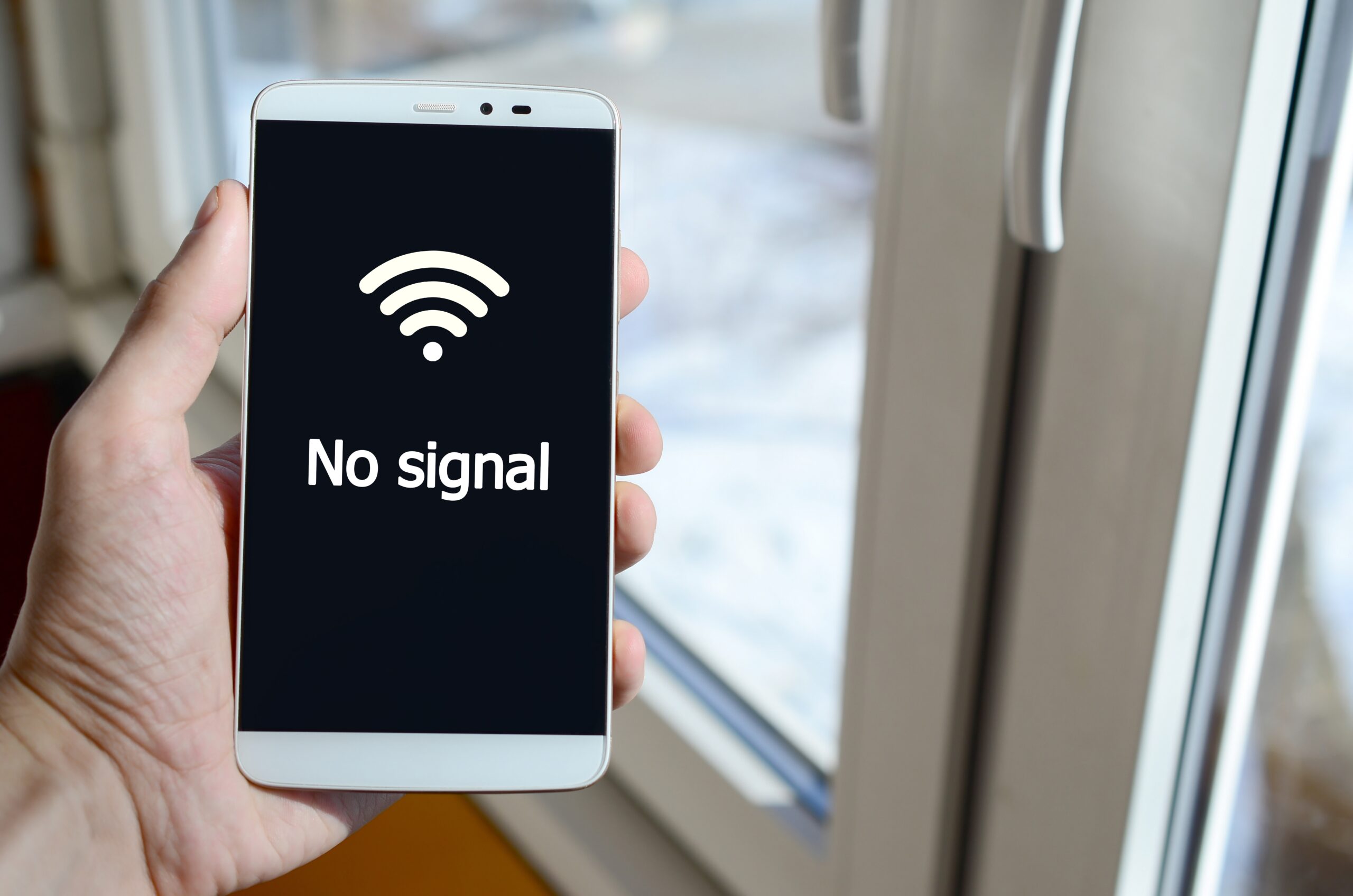 Digital Divide: A person sees a white inscription on a black smartphone display that holds in his hand. No signal