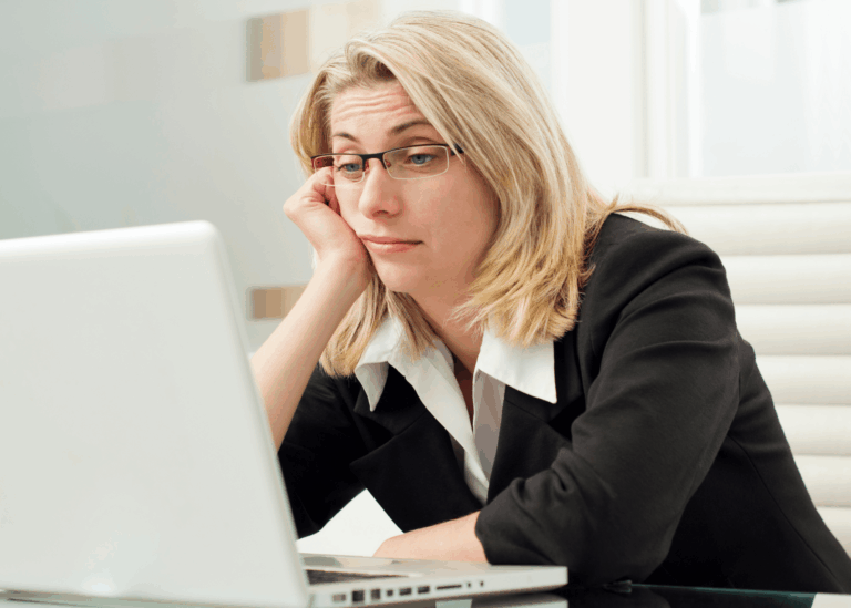 Comparative Positioning: A blonde woman sits at her laptop looking bored