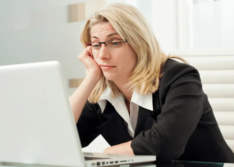 Comparative Positioning: A blonde woman sits at her laptop looking bored