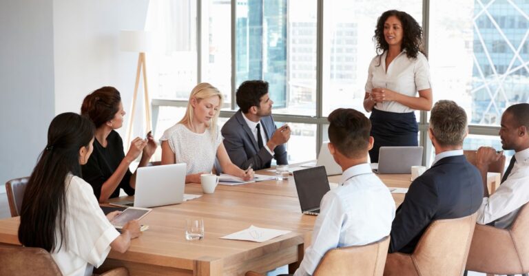 Marketing and communications team meeting in a conference room as a woman presents to colleagues.