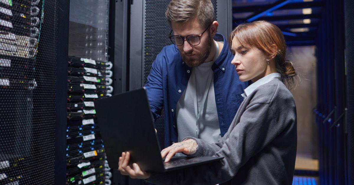 Two professionals reviewing a laptop beside server racks during an incident response