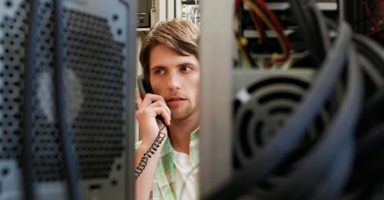 IT professional speaking on a phone between server racks during a cyber incident response